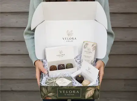 Open e-commerce chocolate packaging box with branded chocolate products and protective paper filling for online delivery